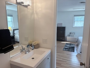 A bathroom with a sink, mirror, and a towel rack.