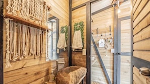 Un intérieur en bois avec un évier en pierre, des étagères en bois ornées de cordes et un miroir.
