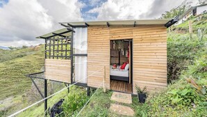 Une cabane en bois avec un lit, une fenêtre et une porte.