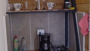 Une cuisine compacte avec un plafond en bois, une machine à café, un évier et divers ustensiles de cuisine.