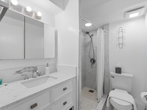 Un baño moderno con un espejo grande, tocador y ducha.