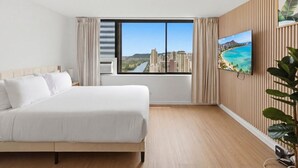 Ein Hotelzimmer mit einem großen Bett, einem an der Wand montierten Fernseher und Blick auf eine Stadtlandschaft durch ein Fenster.