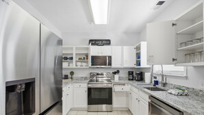 Een moderne keuken met roestvrijstalen apparatuur, witte kastjes en een ingebouwde magnetron.