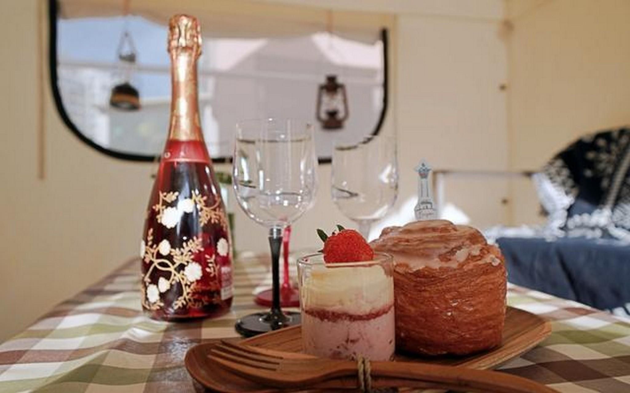 A table with a bottle, a glass, a dessert, and a pastry.