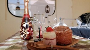 Una mesa con una botella, una copa, un postre y un pastel.