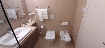 Un baño con lavamanos, inodoro, bidé y toallero.