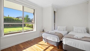 Ein Schlafzimmer mit zwei Betten, einem großen Fenster und Blick auf einen Garten.