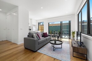 A modern living room with a grey sofa, a coffee table, and a TV stand.