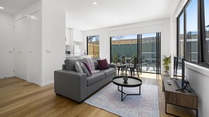 Ein modernes Wohnzimmer mit einem grauen Sofa, einem Couchtisch und einer TV-Konsole.