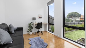 Un salon moderne avec un canapé noir, un bureau et une grande fenêtre.
