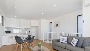 A modern apartment with a dining area, kitchen, and living room.