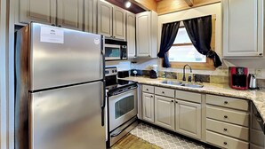 Cocina compacta con electrodomésticos de acero inoxidable, microondas, estufa y pileta.