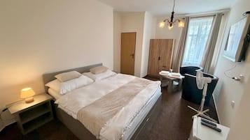 Un dormitorio moderno con una cama grande, lámpara de noche, armario y un escritorio con silla.