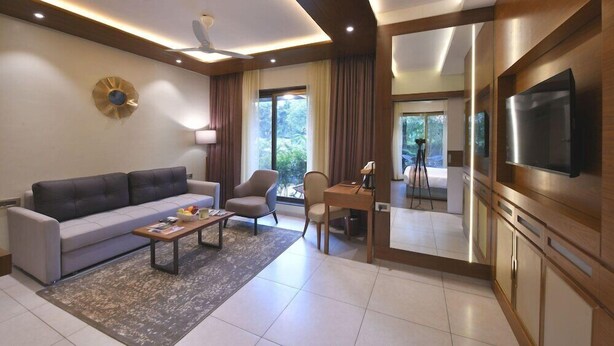 A modern living room with a sofa, chairs, a coffee table, and a television. - Arova Woods Zinc Journey by The Fern, Lonavala (Mawal)