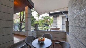 A balcony with a table and chairs, a bowl of fruit, and a view of the outside. - Arova Woods Zinc Journey by The Fern, Lonavala (Mawal)