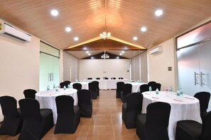 Un salón de conferencias con mesas redondas, sillas negras y techo de madera.