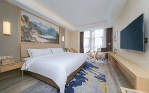 A hotel room with a large bed, a desk, a flat-screen TV, and a painting on the wall. - Vienna International Hotel (Wuhan)
