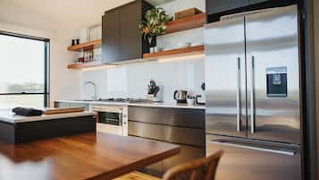 A modern kitchen with a stainless steel refrigerator, wooden countertop, and built-in oven.