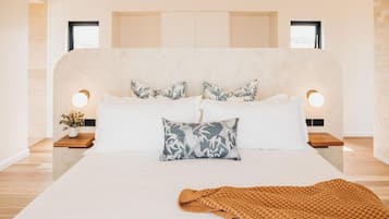 A modern bedroom with a large bed, two bedside tables, and a headboard with built-in lighting.