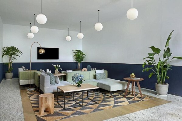 Un salón moderno con un conjunto de sofás, una mesa de centro, lámparas esféricas colgantes y plantas en macetas.