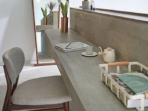 Una cocina moderna con una encimera larga, una silla, una cafetera y una bandeja con un tapete verde.