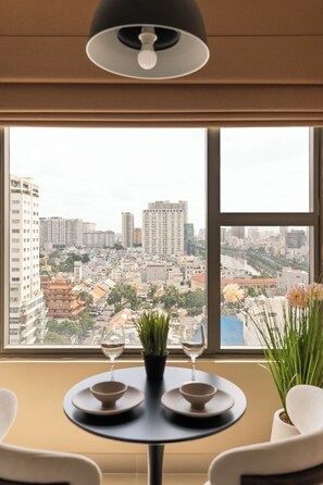 Une table placée devant une fenêtre offrant une vue sur le paysage urbain.