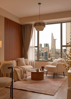 A modern living room with a city view, featuring a sofa, armchairs, a coffee table, and a hanging light fixture. - Maison De Gu Rivergate (Ho Chi Minh City)