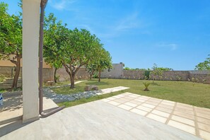 A courtyard with a tiled patio, a stone wall, and a tree-lined area. - Casa Miggiano 6 BR Apartment in Town, Santa Cesarea Terme, Italy (Santa Cesarea Terme)