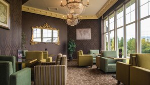 A room with a chandelier, large windows, and patterned wallpaper. - The Holyrood Hotel (Bundoran)