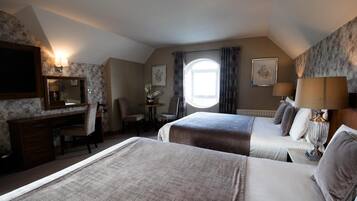 A hotel room with two beds, a desk, a chair, a television, and a window with curtains.