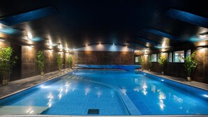 A swimming pool with a tiled floor and walls, surrounded by potted plants and recessed lighting. - The Holyrood Hotel (Bundoran)