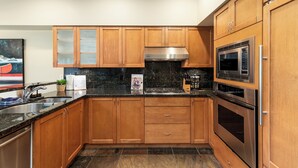 A modern kitchen with wooden cabinets, stainless steel appliances, and a granite countertop. - Modern 3BR | Walk to Whistler Village | Hot Tub | AC | Pet-Friendly (Whistler)