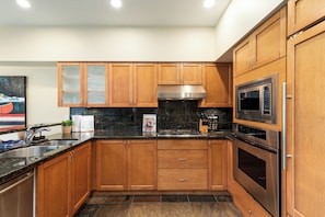 A modern kitchen with wooden cabinets, stainless steel appliances, and a granite countertop. - Modern 3BR | Walk to Whistler Village | Hot Tub | AC | Pet-Friendly (Whistler)