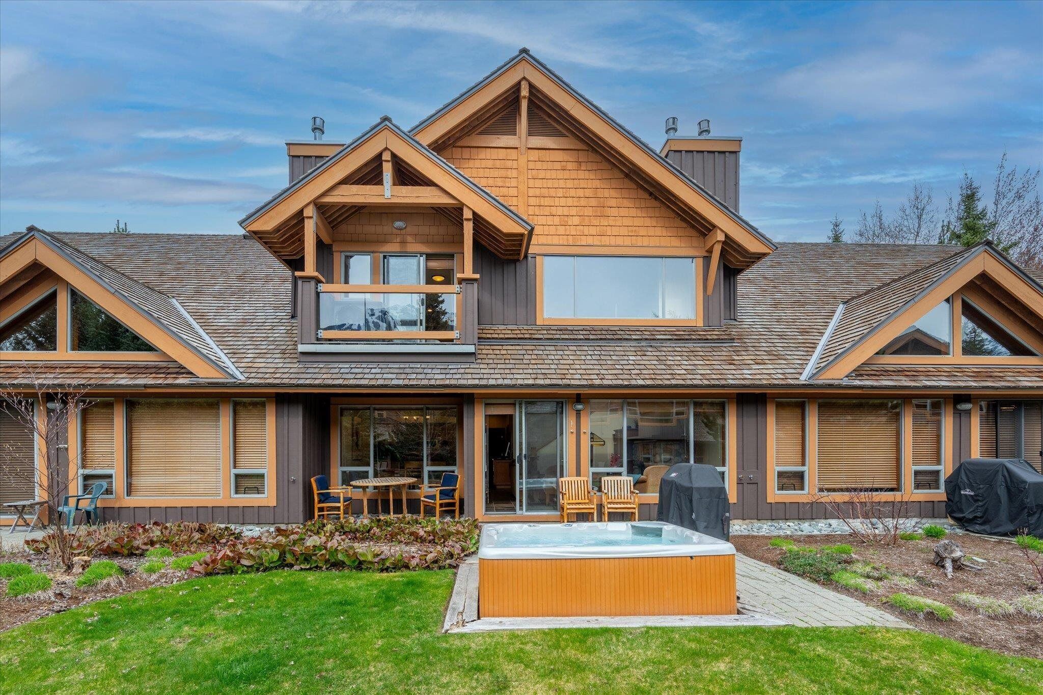 A modern house with a hot tub, a covered patio, and a large window overlooking the yard.