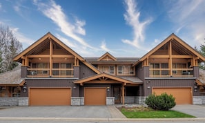 A modern multi-story house with a central entrance, large garage doors, and a stone foundation. - Modern 3BR | Walk to Whistler Village | Hot Tub | AC | Pet-Friendly (Whistler)
