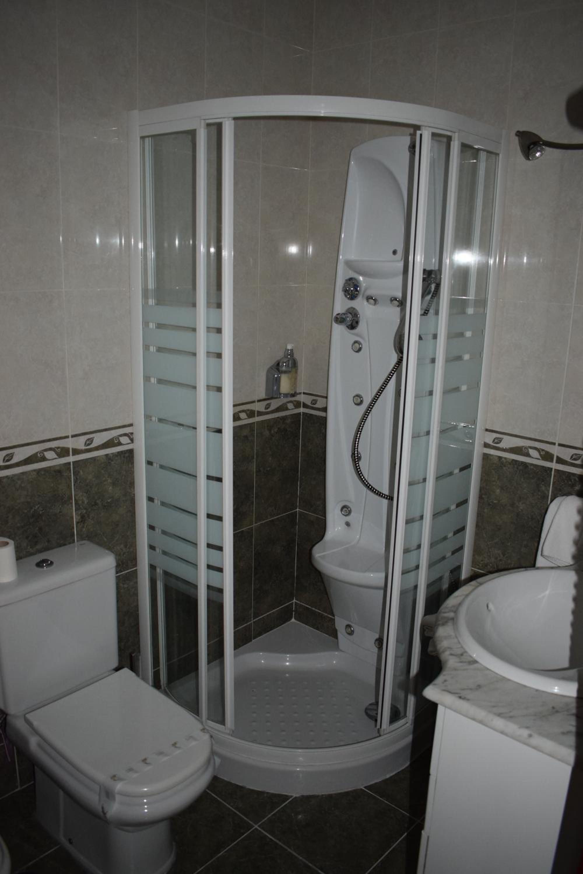 A corner shower enclosure with a glass door, a toilet, and a sink.