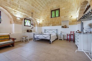 A bedroom with a bed, a chair, a dresser, a small table, and a window with curtains. - Masseria Le Mesolecchie - Ulivo Apt, Crispiano, Italy (Crispiano)