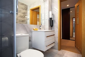 A modern bathroom with a toilet, sink, and mirror.