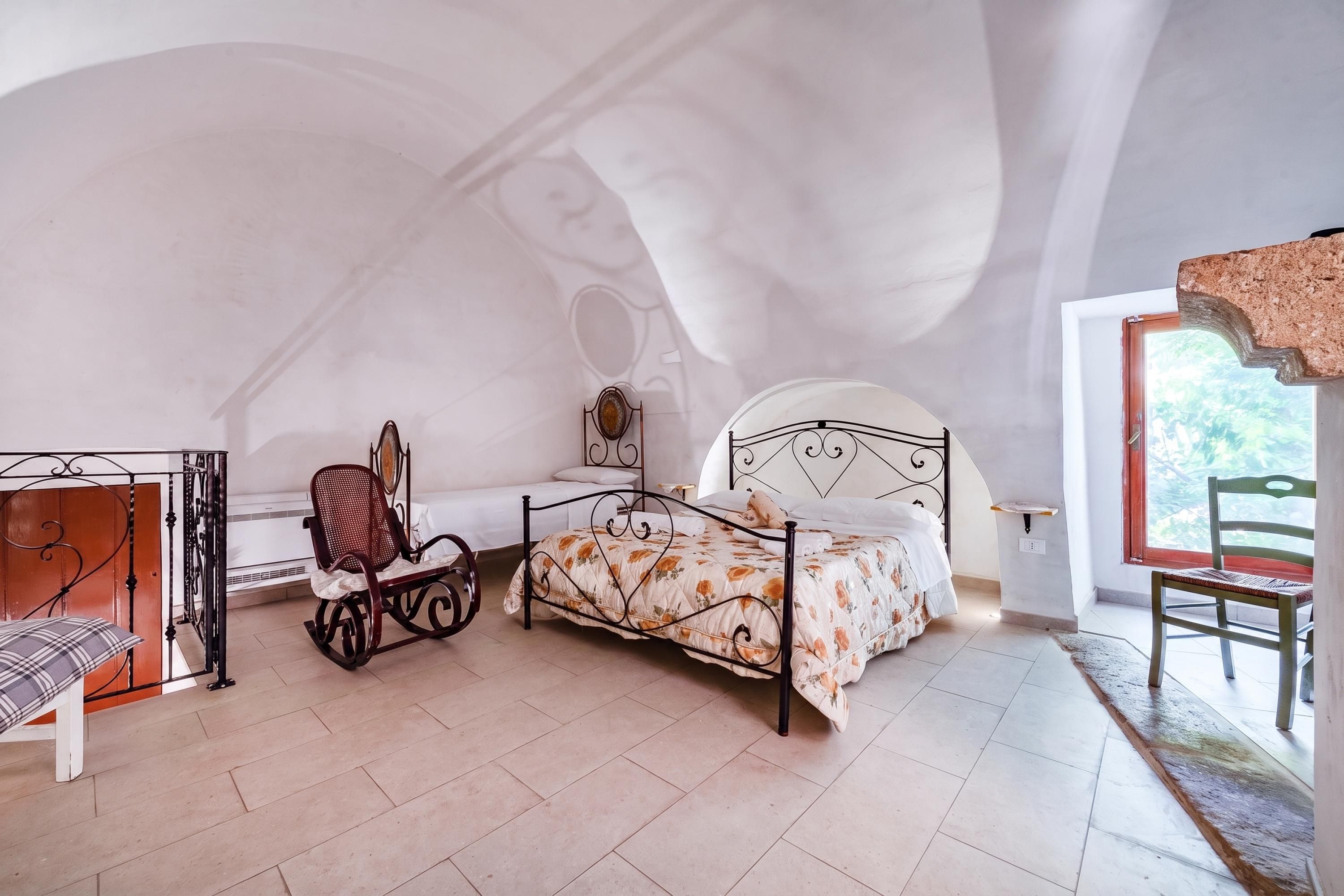 Ein Schlafzimmer mit einem Bett, einem Schaukelstuhl, einem Schreibtisch und einem Sessel.