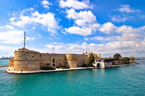A historic fortification with a moat, a flagpole, and a bridge leading to a mainland.