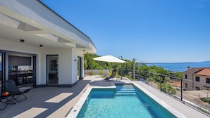 A modern house with a swimming pool, outdoor seating, and a view of the sea. - Pool Villa Soléa /w Panoramic Sea View, Kostrena, Croatia (Kostrena)