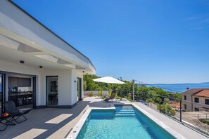 A modern house with a swimming pool, outdoor seating, and a view of the sea. - Pool Villa Soléa /w Panoramic Sea View, Kostrena, Croatia (Kostrena)