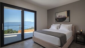 A bedroom with a bed, a painting, a nightstand, and a view through a sliding door. - Pool Villa Soléa /w Panoramic Sea View, Kostrena, Croatia (Kostrena)