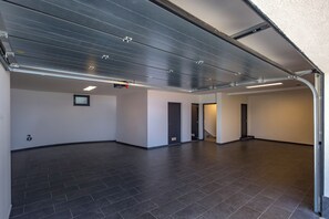 A spacious, empty hallway with a high ceiling, dark floor tiles, and a metal garage door. - Pool Villa Soléa /w Panoramic Sea View, Kostrena, Croatia (Kostrena)