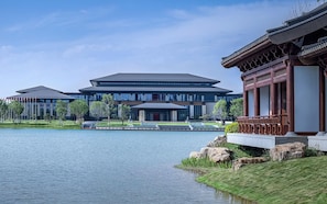 Um edifício moderno com um pavilhão tradicional à beira de um lago tranquilo.