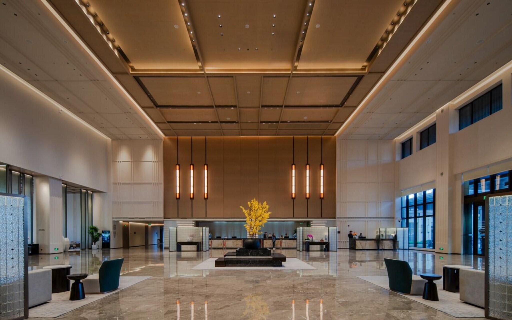 A spacious lobby with a reception desk, seating areas, and a decorative plant centerpiece.