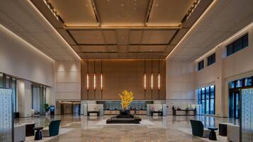 A spacious lobby with a reception desk, seating areas, and a decorative plant centerpiece.
