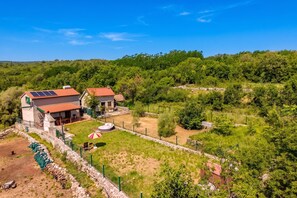 Una propiedad rural con una casa de piedra, un pequeño jardín y un panel solar en el techo.