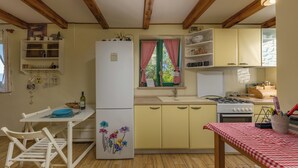 A kitchen with wooden beams, a refrigerator, a stove, and a dining table with chairs. - Holiday Home Ruby, Polje, Croatia (Polje)