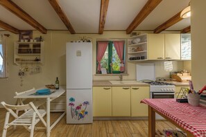 A kitchen with wooden beams, a refrigerator, a stove, and a dining table with chairs. - Holiday Home Ruby, Polje, Croatia (Polje)